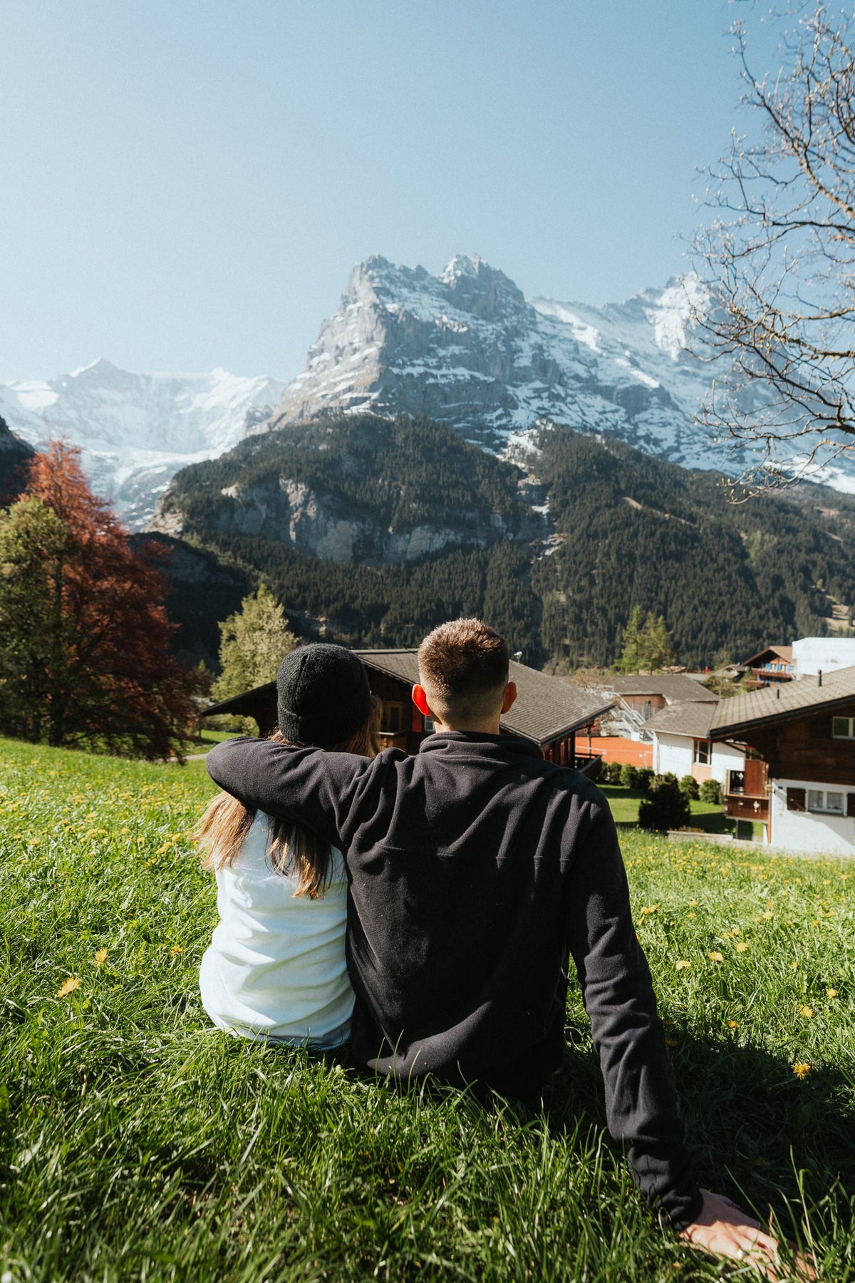 Lachie and Tarsh sitting together in a meadow looking towards the mountains.