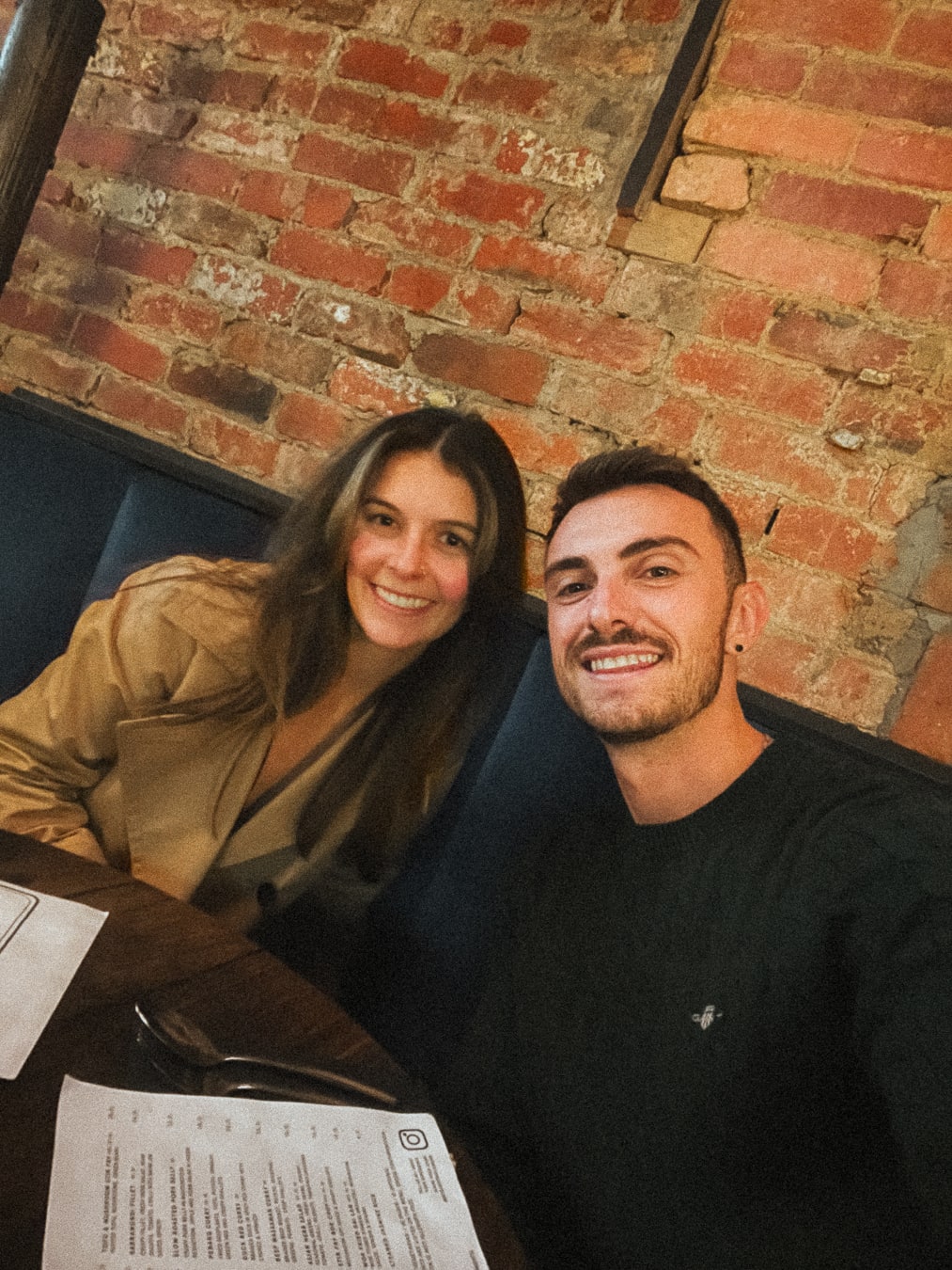 Lachie and Tarsh smiling together at a café table in Daylesford.